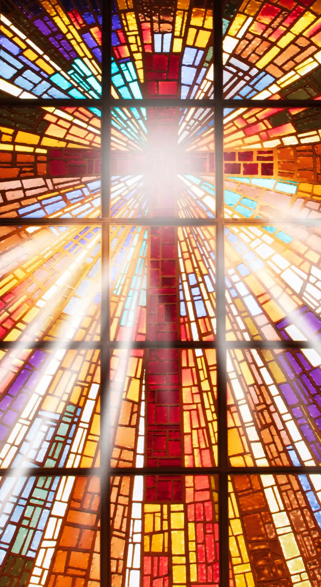 Sunlight beams through a vibrant stained glass window with a red cross.