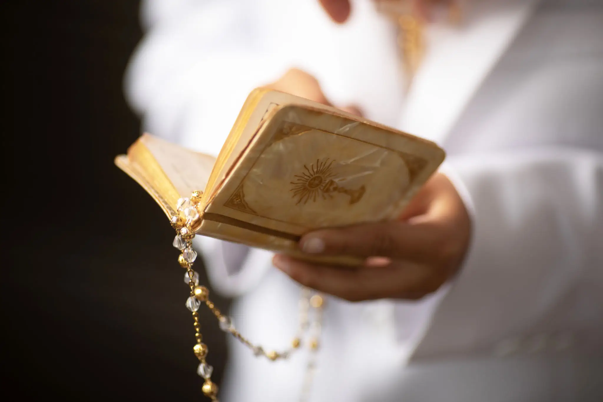 Person holding an old prayer book with a rosary.