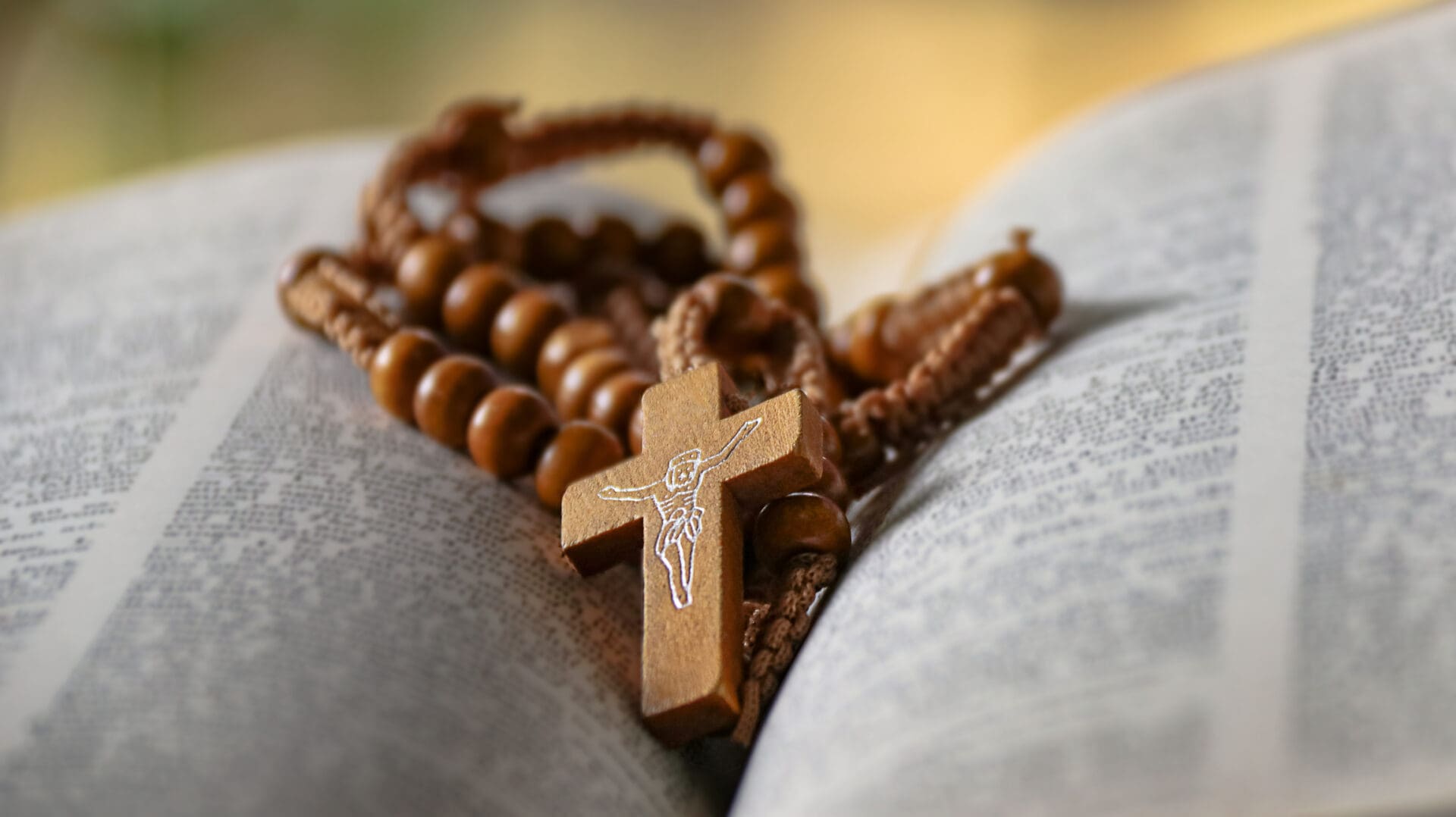 Wooden rosary with cross on book