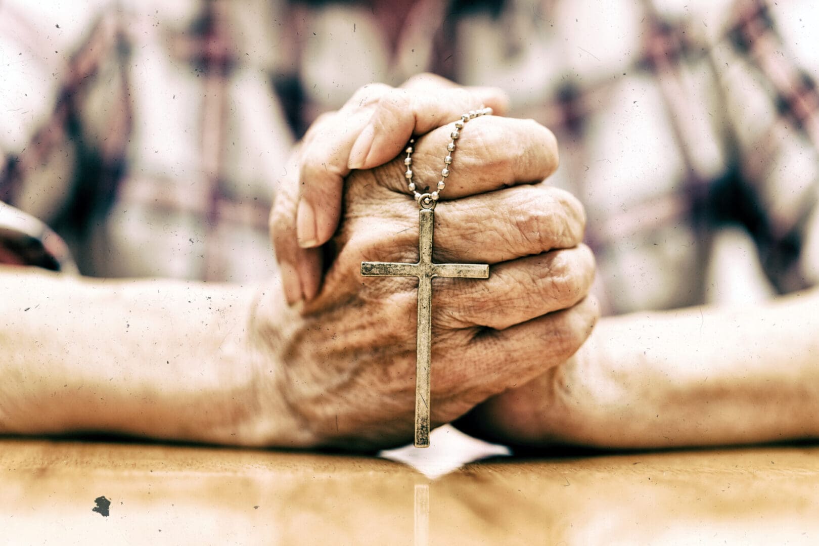 Elderly hands gripping a crucifix tightly