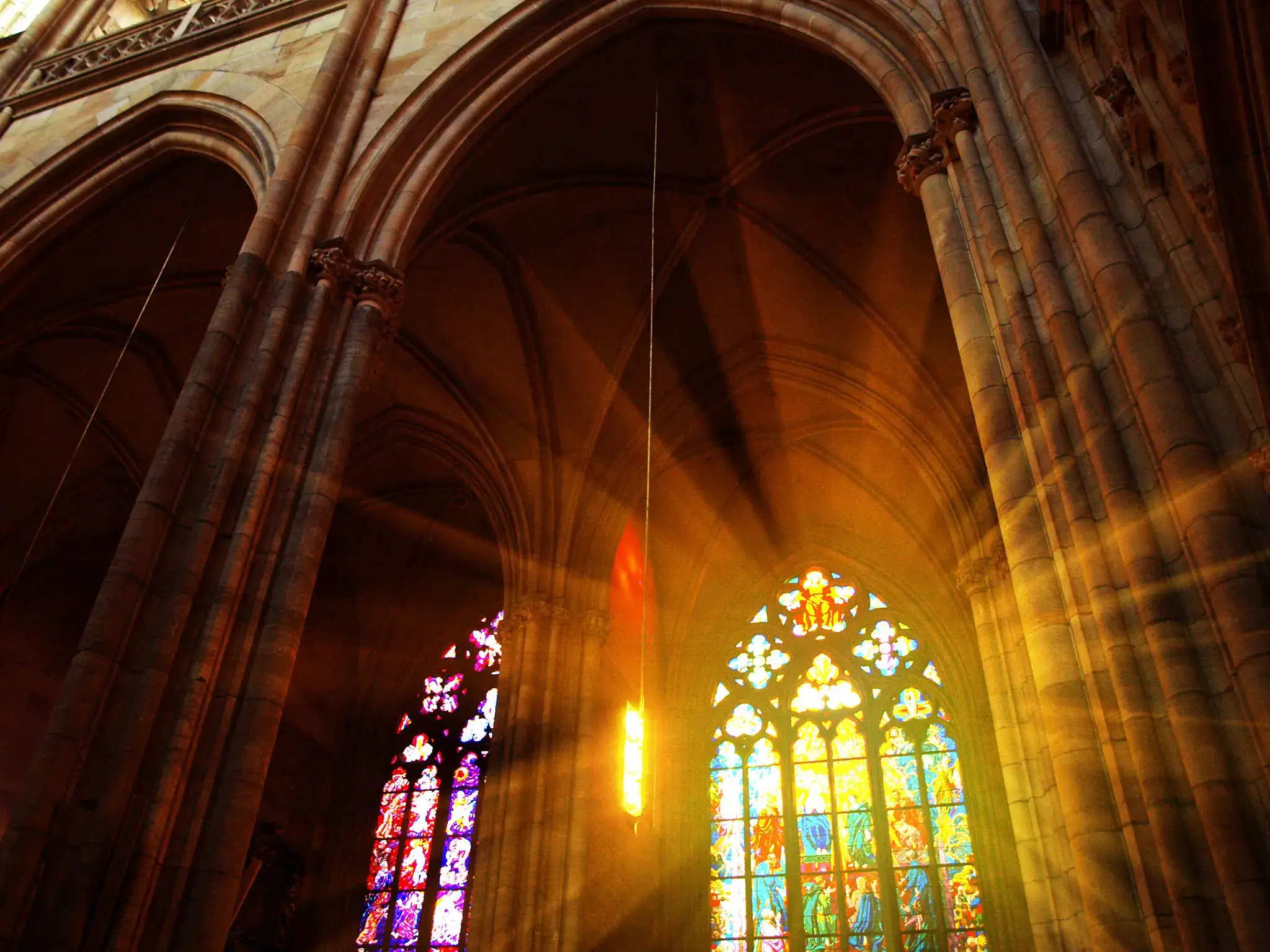 Sunlight streaming through colorful stained glass windows in a cathedral.