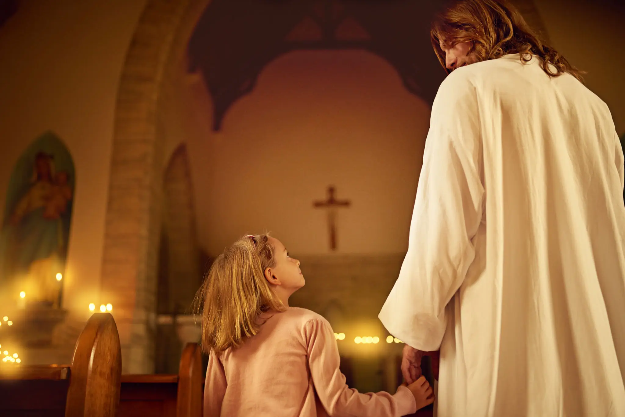 A child and a man holding candles in a church.