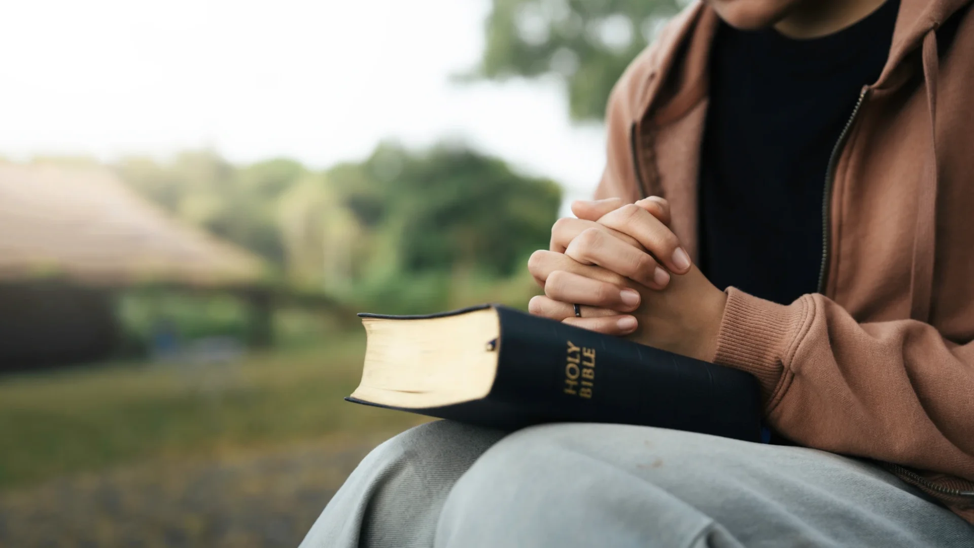 Person praying with Bible outdoors